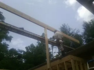 Carpenter setting a ridge beam over a new addition frame — Ice Dam Removal by Roofing Brothers in Lindsey