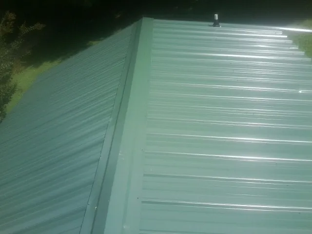 New green metal panels meeting at the ridge of a roof — Flat Roof Repair work by our crew in Lindsey