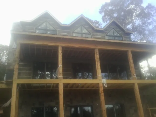 Dormers and porch framing on a large log home under construction — Roof Coating work by our crew in Lindsey