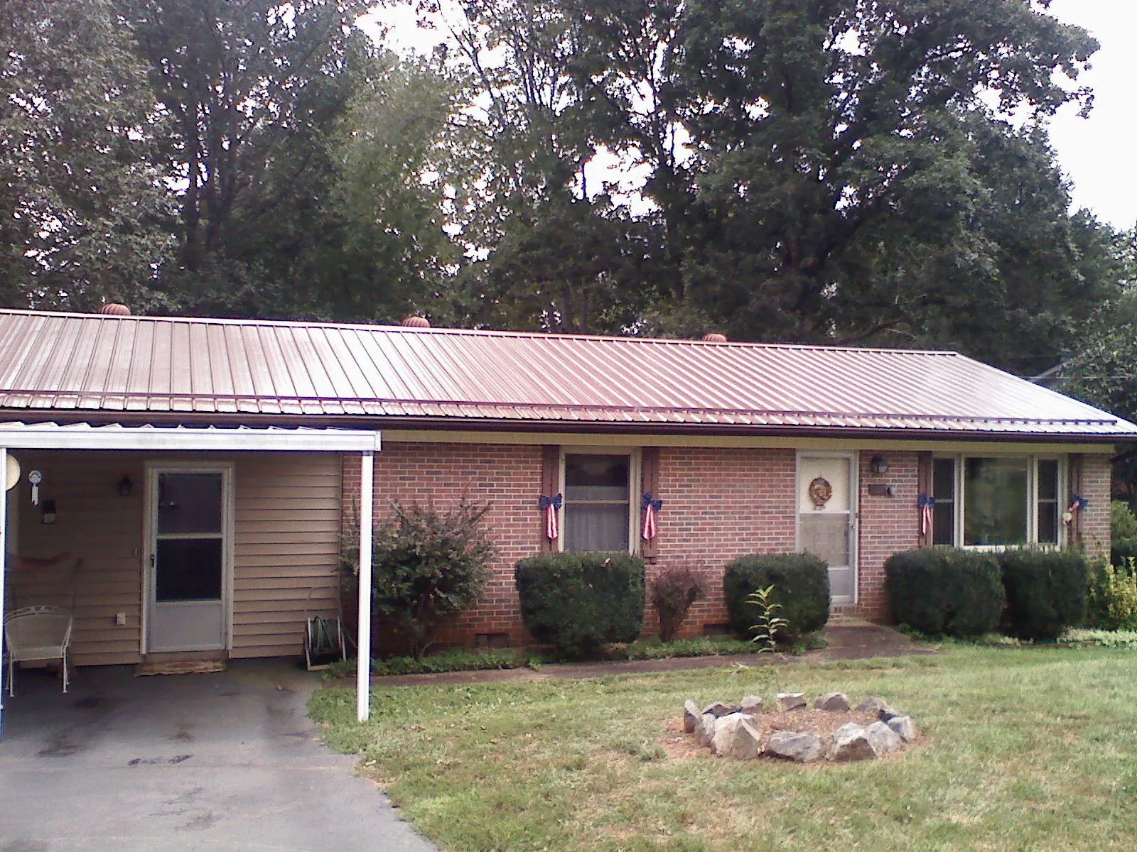 Bronze metal roof and carport on a brick ranch home — Roof Repair work by our crew in Lindsey