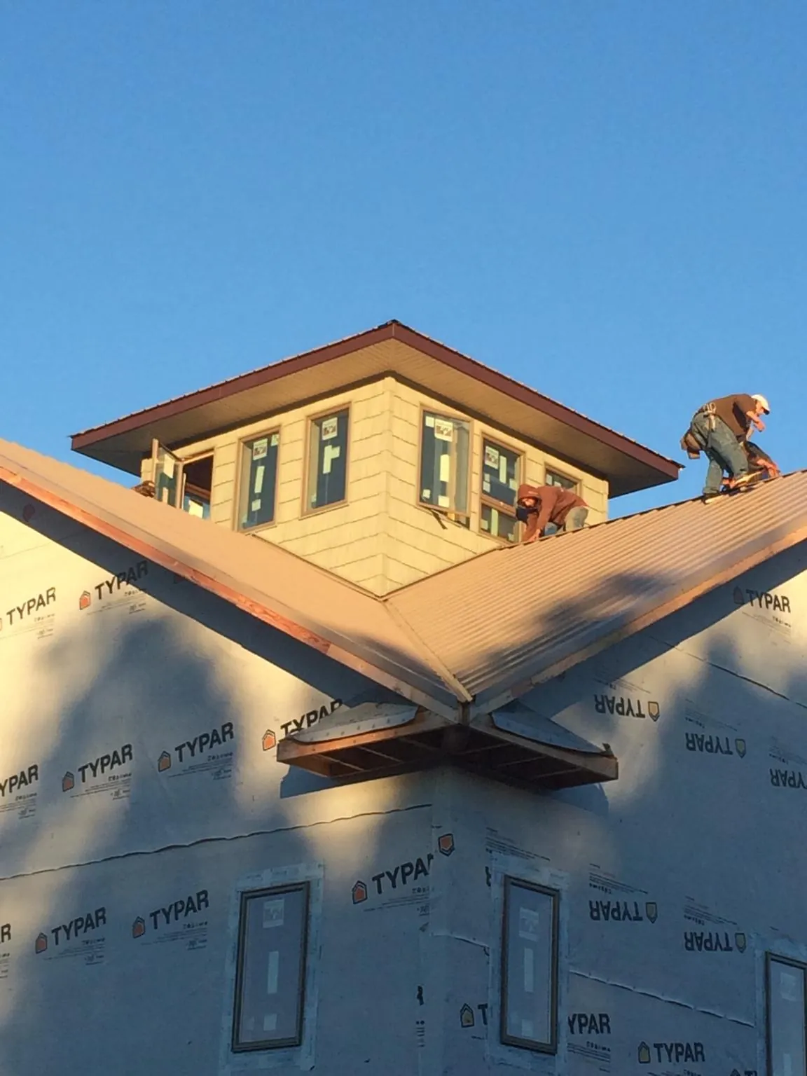 Roofers working around a rooftop cupola on a new metal roof at sunset — Roof Waterproofing in Lindsey by Roofing Brothers